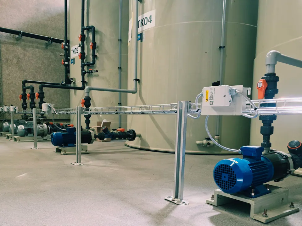 Rad av processtankar med röranslutningar, ventiler och en blå pump i förgrunden
