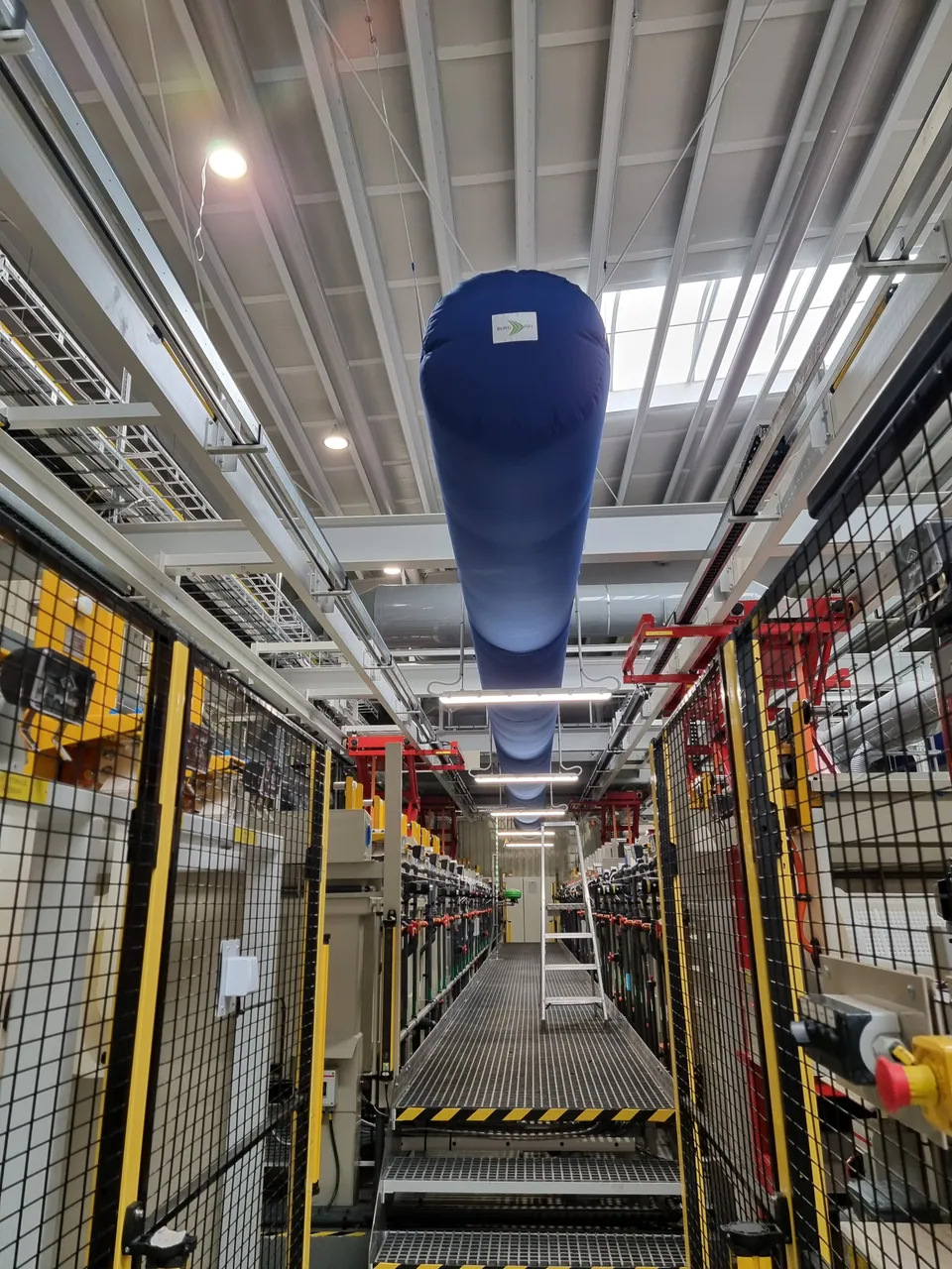 Blå textilkanal för ventilation ovanför en produktionslinje i en industrihall